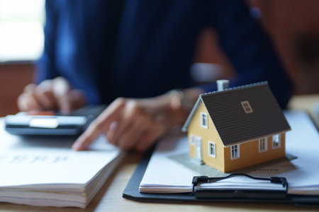 A house seller in a blue suit is working with a calculator at a desk. She is holding a piece of paper and appears focused on her calculations.の写真素材