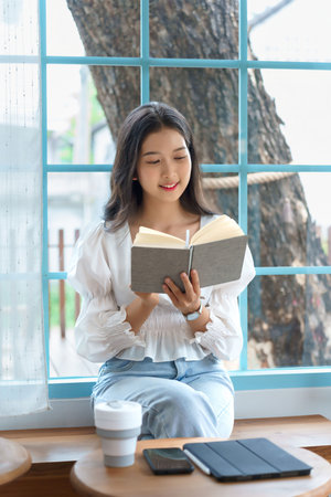 Young asian businesswoman enjoying to reading literature the book and relaxation with drinking...