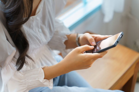Closeup hands of young asian businesswoman use smartphone to chat texting message and checking email after analysis strategy about investment and planning of new startup project while working in cafe.の写真素材