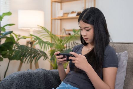 Young asian gamer women using smartphone to playing video game with having fun and happiness while...