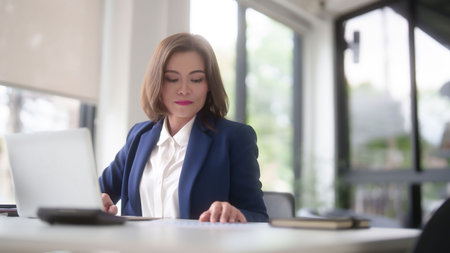 Asian businesswomen reading marketing business report to checking financial chart data and typing data on keyboard laptop while analyze investment and market stock of new startup in outside office.の写真素材