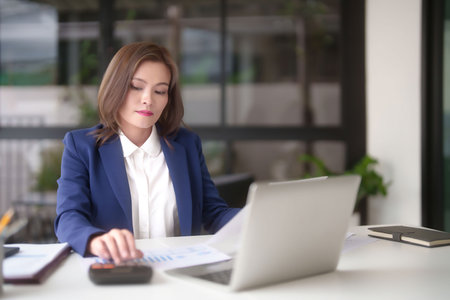 Asian businesswomen reading marketing business document and using calculator calculate statistics to checking finance chart while analyze investment and market stock of new startup in outside office.の写真素材