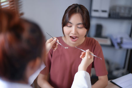 Asian dentist doctor women using explorer mirror tool to examining teeth of patient and explaining about oral dental treatments while discussion about dental health and healthcare in dental clinic.の写真素材