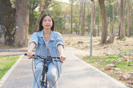 Young asian women having happiness and enjoying with nature view while cycling bicycle on the street in the park to relaxation and exercise with journey travel trip for healthy wellness lifestyle.の写真素材