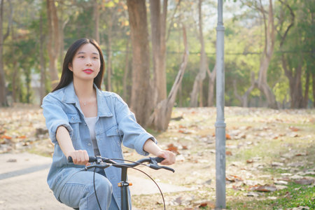 Young asian women having happiness and enjoying with nature view while cycling bicycle on the street in the park to relaxation and exercise with journey travel trip for healthy wellness lifestyle.の写真素材