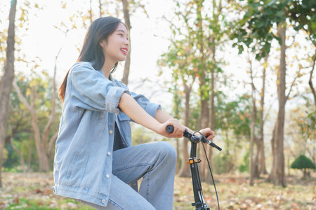 Young asian women having happiness and enjoying with nature view while cycling bicycle on the street in the park to relaxation and exercise with journey travel trip for healthy wellness lifestyle.の写真素材