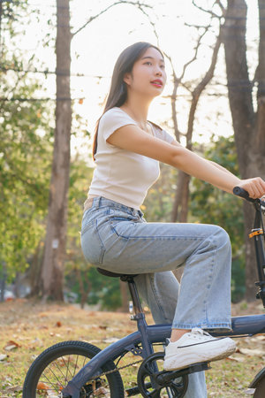 Young asian women riding bicycle to exercise on the street and enjoying with nature view in the park while having happiness to relaxation with journey travel trip for healthy wellness lifestyle.の写真素材