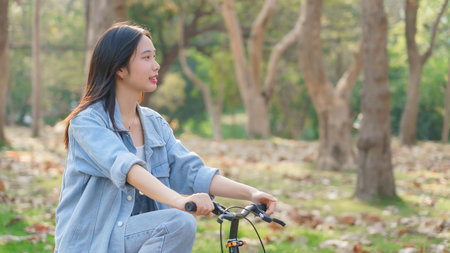 Young asian women having happiness and enjoying with nature view while cycling bicycle on the street in the park to relaxation and exercise with journey travel trip for healthy wellness lifestyle.の写真素材