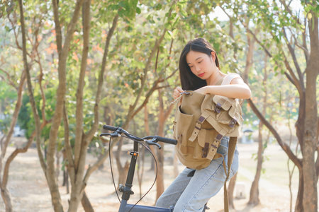 Young asian women sitting on bicycle and opening backpack to resting after cyclist bicycle in the nature park while having happiness and relaxation with journey travel trip for healthy lifestyle.の写真素材