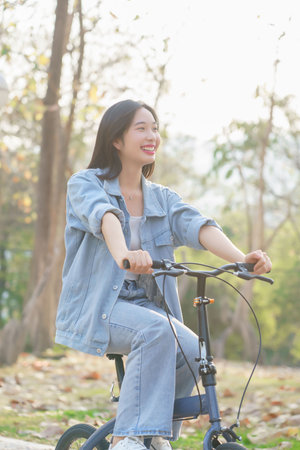 Young asian women having happiness and enjoying with nature view while cycling bicycle on the street in the park to relaxation and exercise with journey travel trip for healthy wellness lifestyle.の写真素材