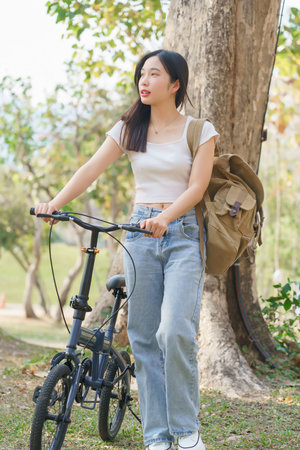 Young asian women with backpack having happiness and enjoying to walking with bicycle while relaxation with journey travel trip for healthy lifestyle after cycling bicycle in the nature park.の写真素材