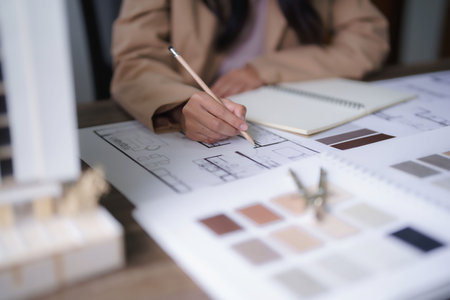 Female architect designing architecture interior and sketching construction project on blueprint.の写真素材