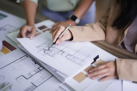 Two female architects discussing about interior designing building project and drawing on blueprint.の写真素材