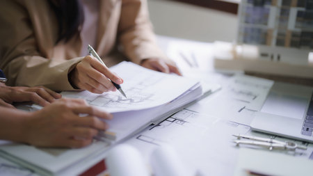Two female architects discussing about interior designing building project and drawing on blueprint.の写真素材