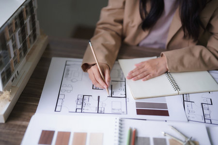 Female architect designing architecture interior and sketching construction project on blueprint.の写真素材