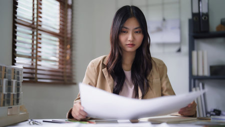 Female architect checking sketch of interior building project and color sample on blueprint.の写真素材