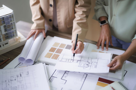 Two female architects discuss and brainstorm about interior designing building project on blueprint.の写真素材