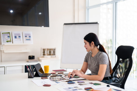 Focused interior designer planning color concepts and working with material samples at design deskの写真素材