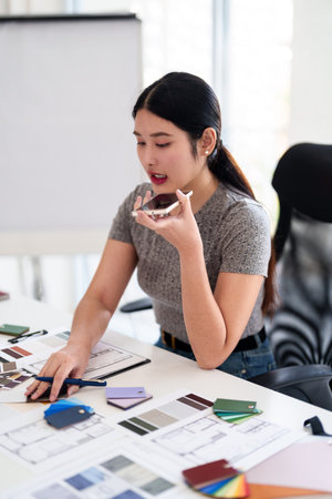 Interior designer making business call while working on color and material selection at design studio deskの写真素材
