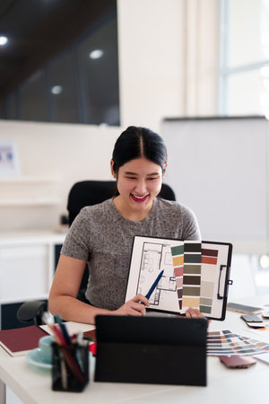 Young architect presenting interior design ideas through tablet during online meeting in creative officeの写真素材
