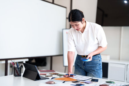Young architect selecting materials and color swatches while standing at modern interior design workstationの写真素材