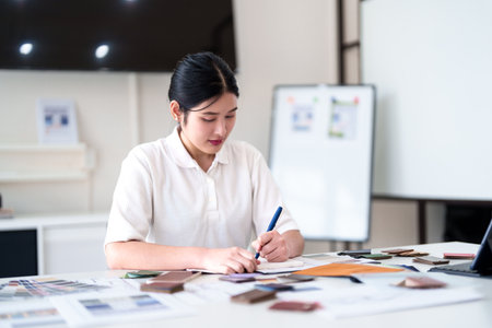 Focused interior designer planning color concepts and working with material samples at design deskの写真素材