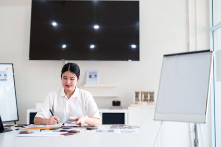 Focused interior designer planning color concepts and working with material samples at design deskの写真素材