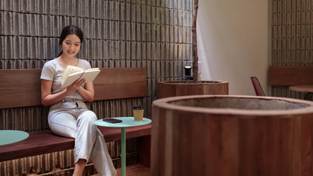 Peaceful young woman reading her diary and reflecting during quiet moment at serene outdoor cafeの写真素材