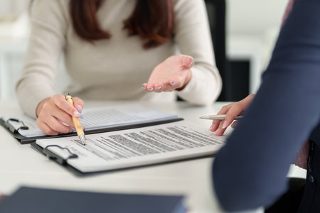Two adult Muslim women are in a business meeting, reviewing a contract Asian women are looking over paperwork to discuss Collaborationの写真素材
