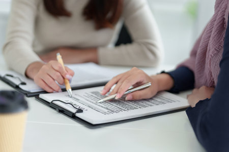 Adult Asian women in hijab collaborate on a business contract. Muslim Businesswomen shake hands after the partnership contract agreement, businesswomen planning for financial successful.の写真素材