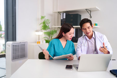 Asian adult doctor and nurse reviewing medical records using a laptop in clinic, consulting on patient data and treatment plan in a healthcare team meeting. Discussing for medical solution.の写真素材