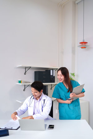 A team of Asian doctor and nurse working together in the hospital office to discuss patient medical record with smile expressing their teamwork for healthcare servicesの写真素材