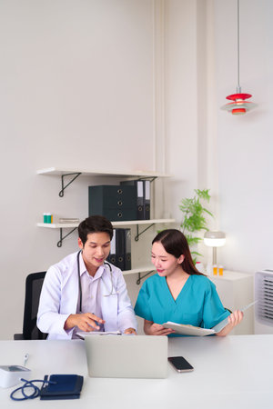 Two Asian healthcare workers an adult doctor and a nurse are working together reviewing patient records in a bright office They discuss treatment options for better outcomesの写真素材