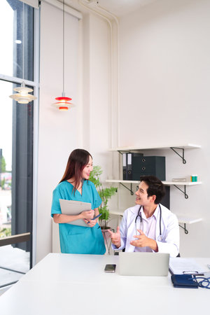 An Asian adult doctor and nurse are discussing patient care in a modern clinic, showing teamwork collaboration. Medical professionals in a hospital setting consulting on casesの写真素材