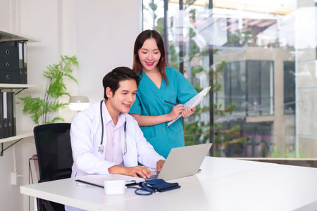 Asian doctor and nurse working together in modern clinic using a laptop for patient data. Medical team providing quality healthcare services with collaboration and technologyの写真素材