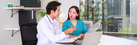 Adult Asian doctor and nurse analyzing patient medical records report using computer in office. Discussing diagnosis and treatment plan for healthcare service solutions in the clinicの写真素材