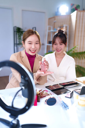 Two young Asian women are live streaming online tutorial for makeup and skincare product. The beauty vlogger shares beauty tips for skincare product and makeup online.の写真素材