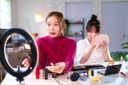 Young Asian women creating beauty content for online platforms using makeup products ring light. Content creator providing makeup tutorials for her social media beauty vlogs.の写真素材