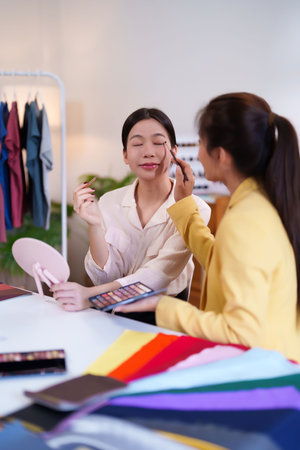 Adult Asian women are doing makeup with personal color analysis. One woman getting her makeup done by artist. Colorful fabric swatches on the white tableの写真素材