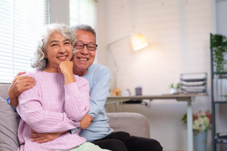 This heartwarming image captures the essence of a loving older Asian couple enjoying retirement life at home. They embrace, showcasing enduring love and companionship.の写真素材