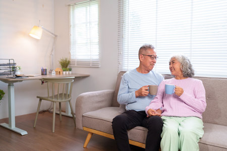 This heartwarming image showcases an older Asian couple enjoying coffee together at home fostering a life full of love and joy during retirement.の写真素材
