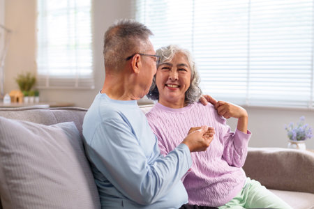 This heartwarming image shows an older Asian couple spending quality time together in their cozy home celebrating aging and embracing companionship indoorsの写真素材