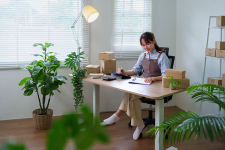 Asian young woman working on the tablet for online marketing and e-commerce business at home office...