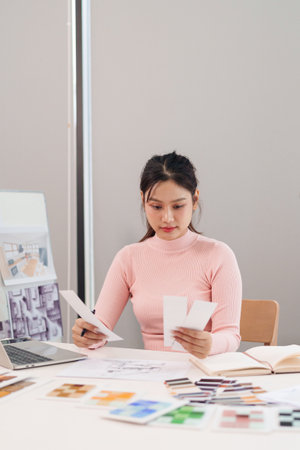 Young Asian woman UI designer working on a website design project selecting color palette from swatches. She is creating a modern, and intuitive user interfaceの写真素材