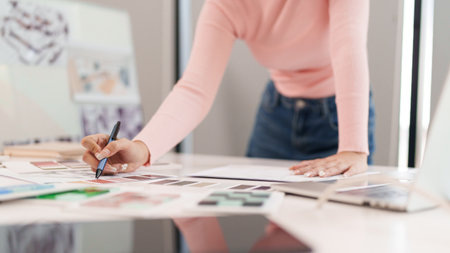 This image showcases an adult Asian woman interface designer at work selecting a color palette samples for new website and application design creative processの写真素材