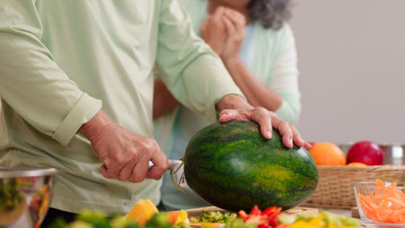Older Asian hands expertly cutting fresh watermelon vibrant kitchen scene healthy cooking meal preparation at home domestic lifestyle nutritious foodの写真素材
