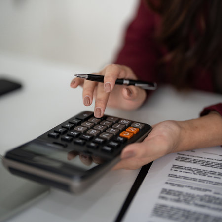 Adult hands precisely calculate numbers with a calculator and pen. Focus on financial planning property investment home buying process. Professional work desk.の写真素材