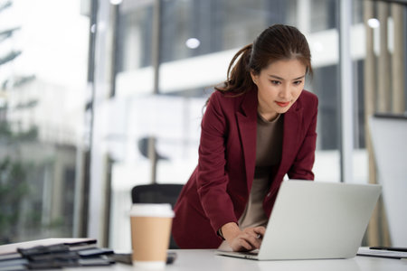 Asian adult professional actively researching market data using a laptop for effective property sales strategyの写真素材