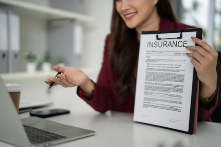 Experienced Asian adult woman real estate agent professionally explains essential property insurance details during home purchase consultationの写真素材