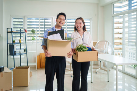 Asian adults collaboratively build table joyful office setup in bright modern workspace teamwork...